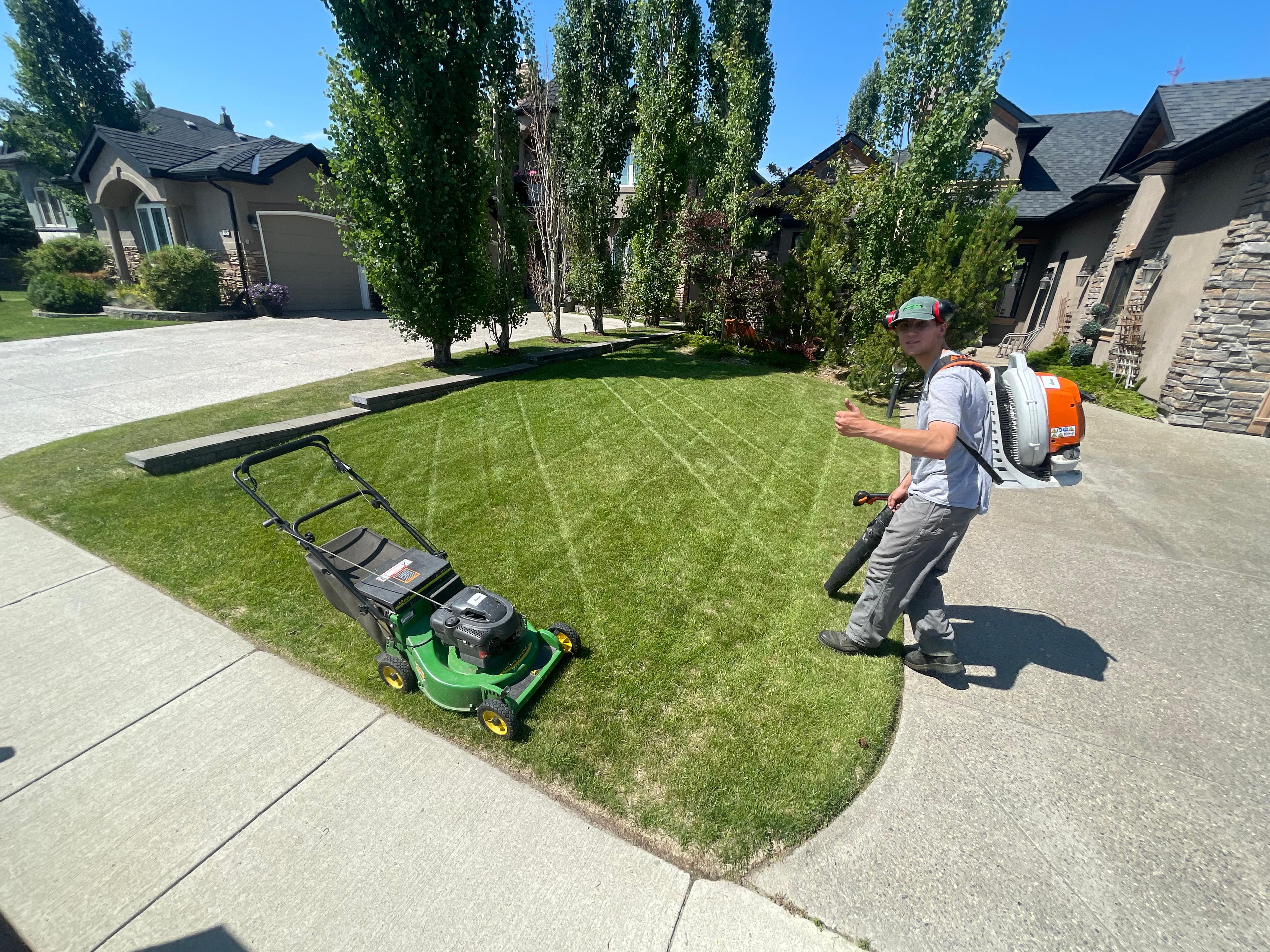 Absolute Yardworks team mowing residential lawn in Calgary
